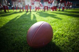 image of American football with team standing in a huddle 